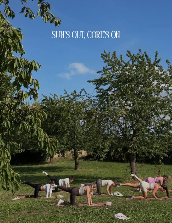 Groep doet Pilates buiten op het gras onder de bomen